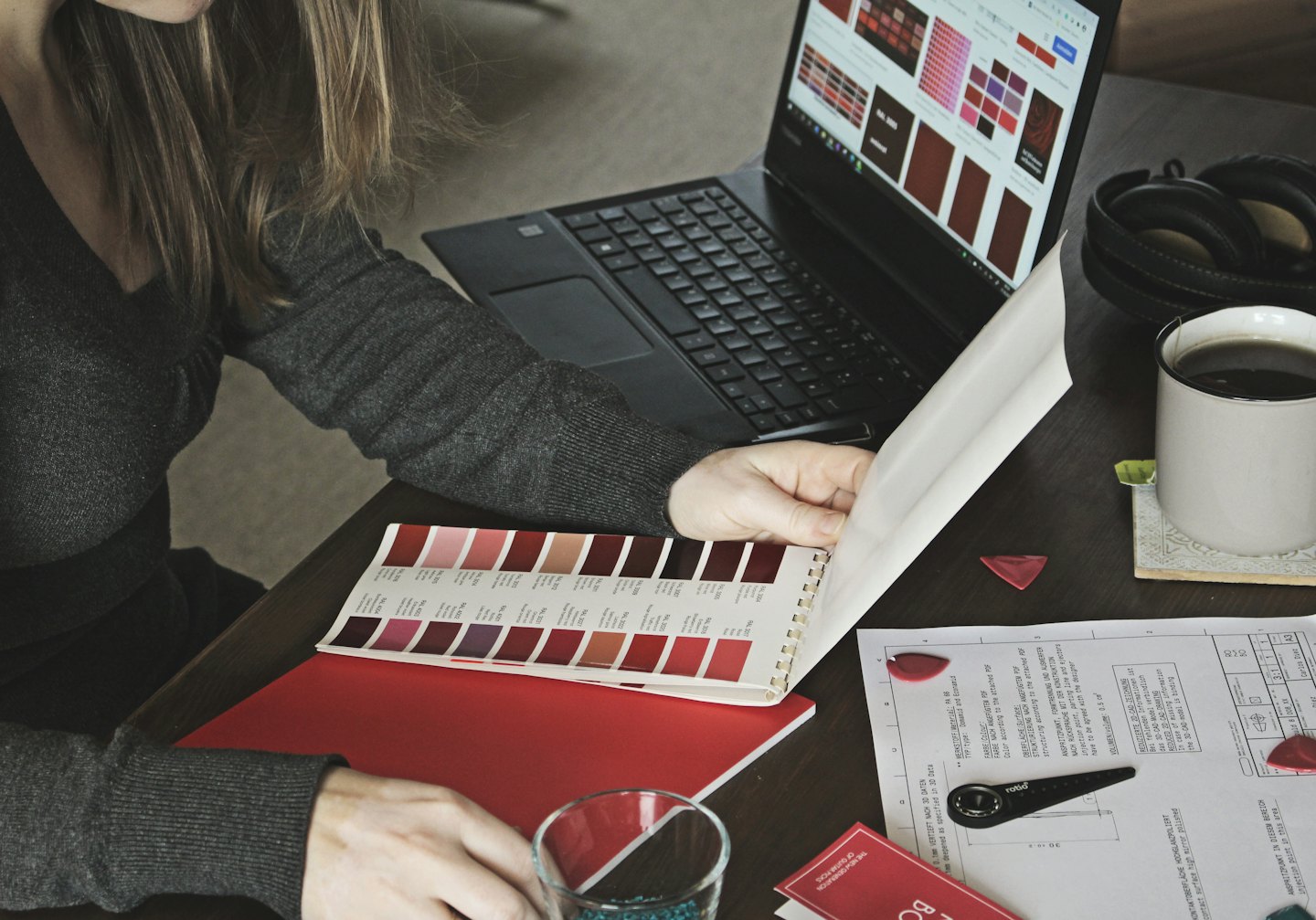 Una designer esamina campioni di colore su un laptop e su un libro.